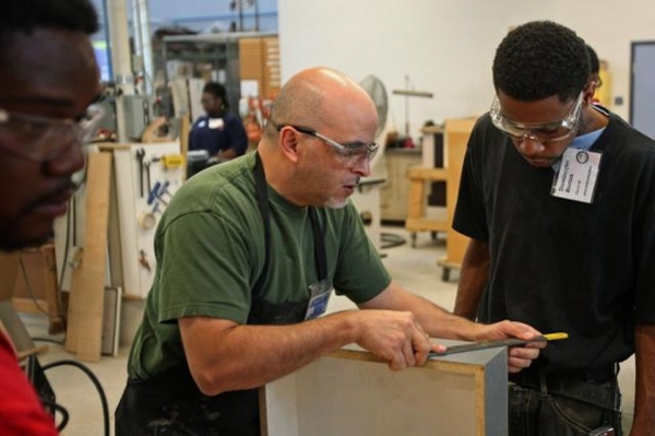 Instructor helps a student participating in a woodworking manufacturing training program in Chicago, Illinois, U.S. Photographer: Tim Boyle/Bloomberg Charlie Negron